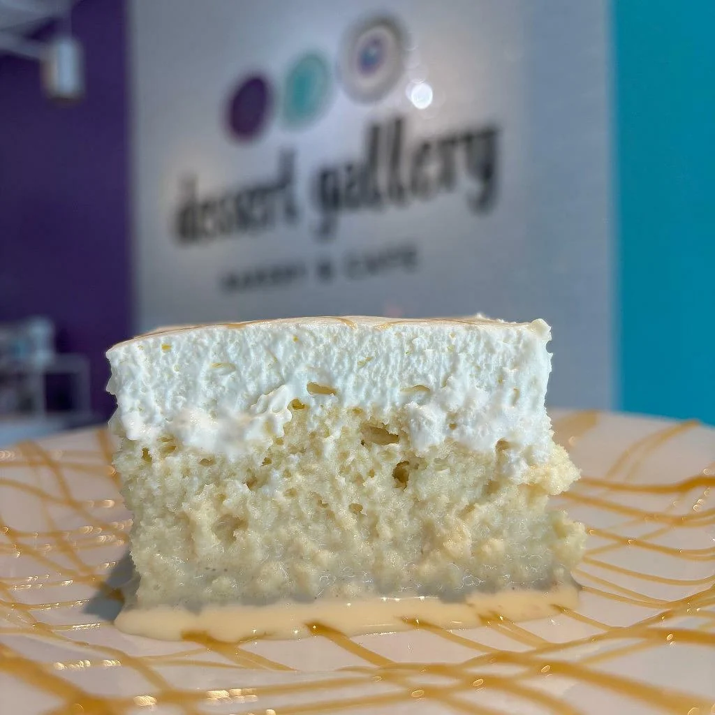 Side view of a tres leches slice showing the soaked sponge under whipped cream